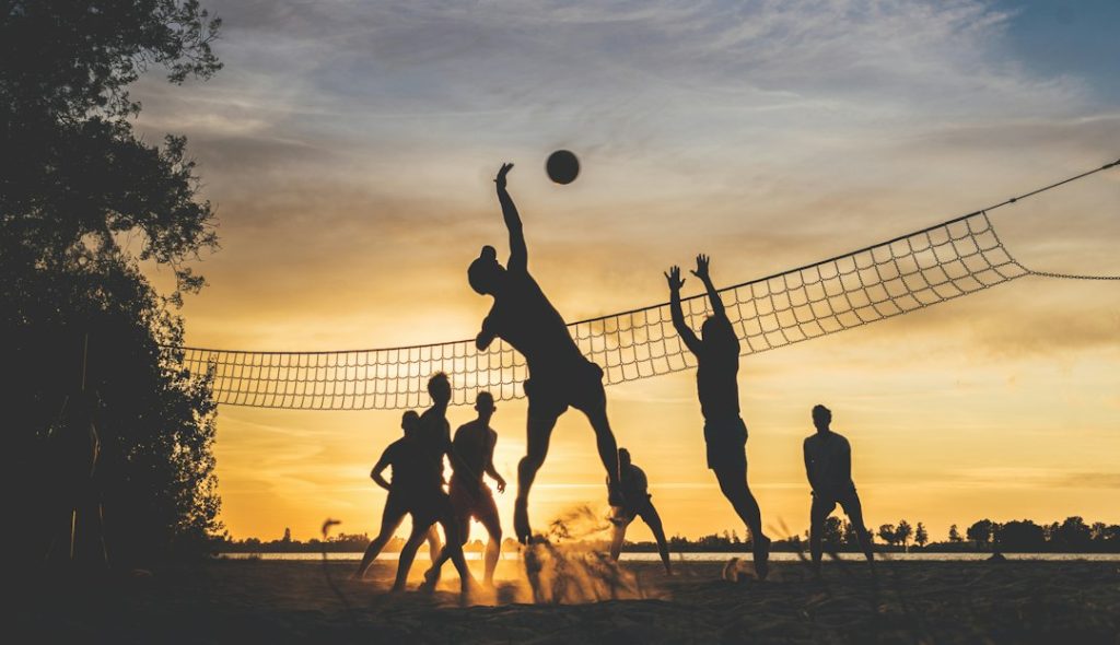 Friends playing beach volleyball together as a team