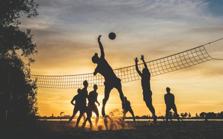 Friends playing beach volleyball together as a team