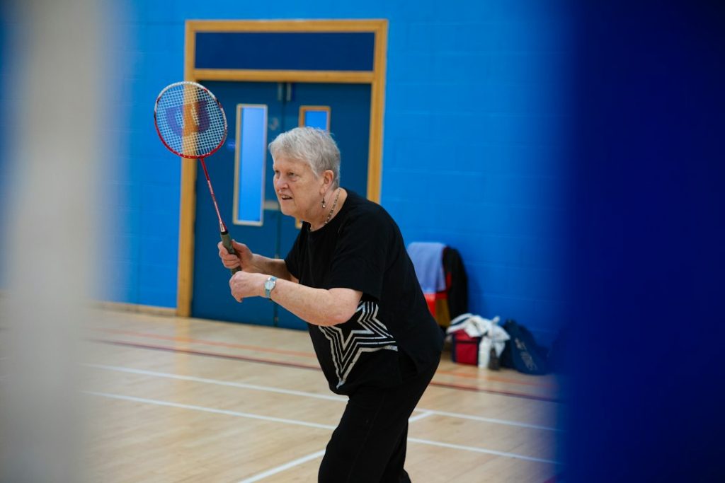 Adult beginners learning badminton together in a gymnasium